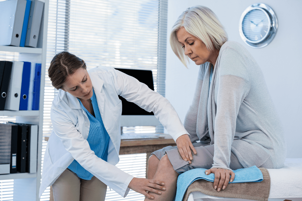 Лікар проводить огляд пацієнтки з артрозом колінного суглоба